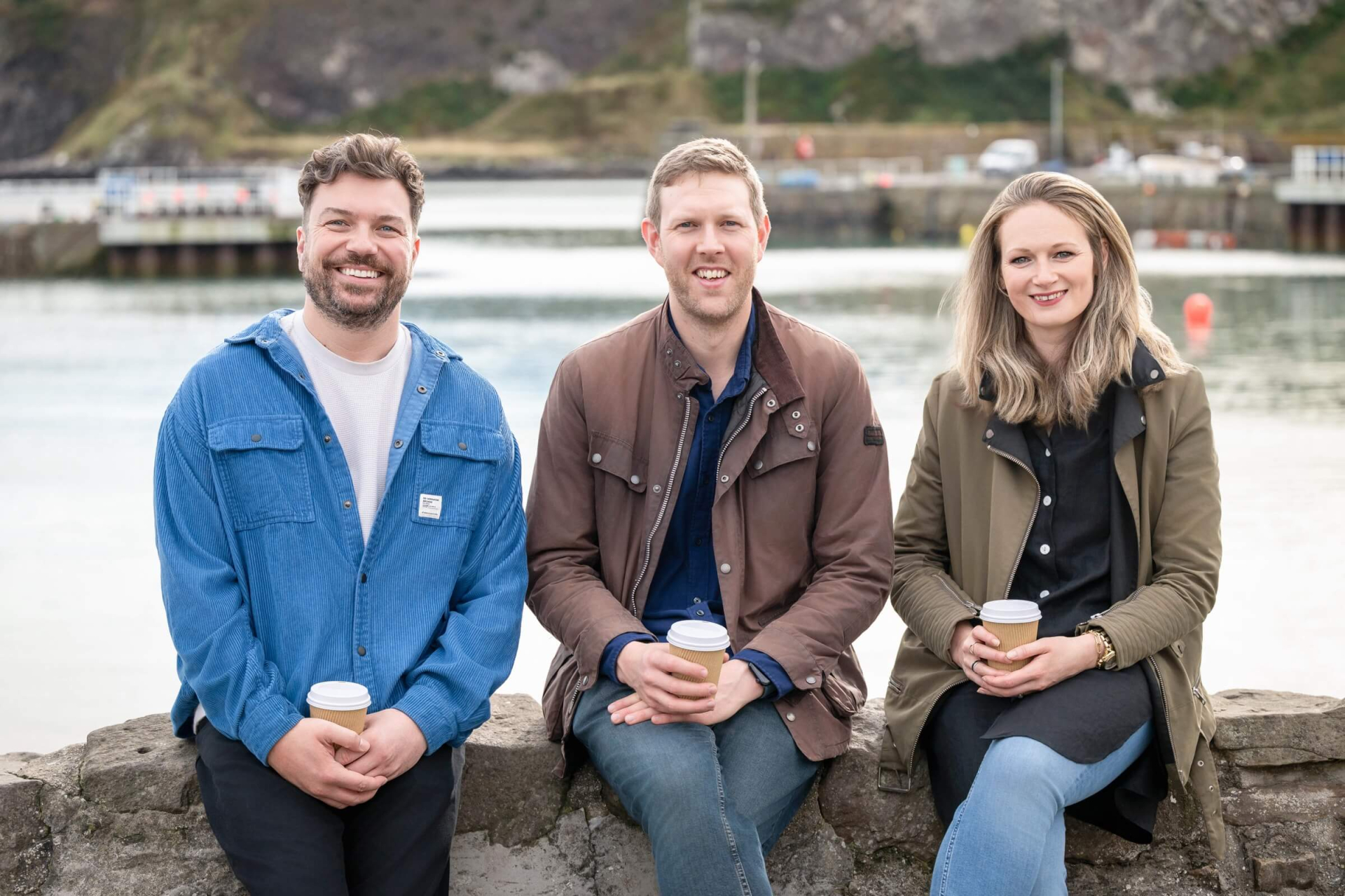 Ben, Rory and Lizi all sitting on a wall.